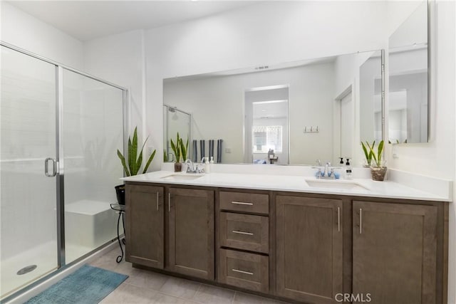 bathroom featuring a shower stall, tile patterned flooring, double vanity, and a sink