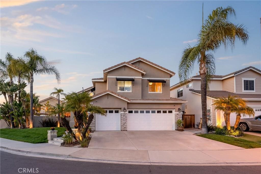 20 Beaulieu Ln, Lake Forest, CA 92610 - traditional-style home featuring stucco siding, stone siding, an attached garage, driveway, and a tiled roof