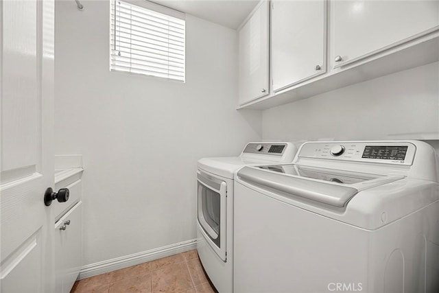 clothes washing area with independent washer and dryer, baseboards, and cabinet space
