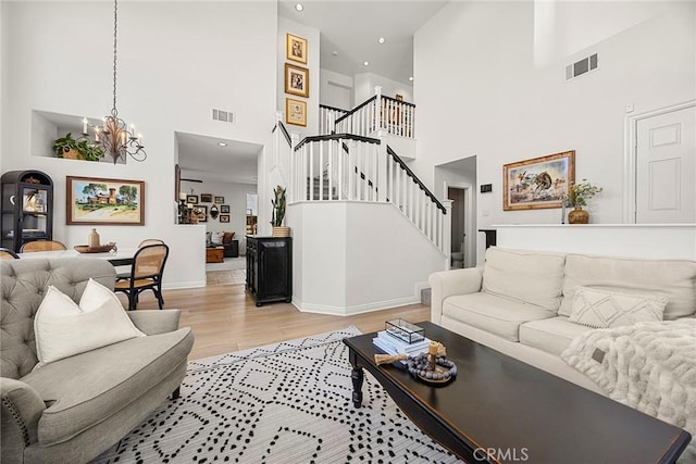 living area with a chandelier, a towering ceiling, visible vents, and stairway
