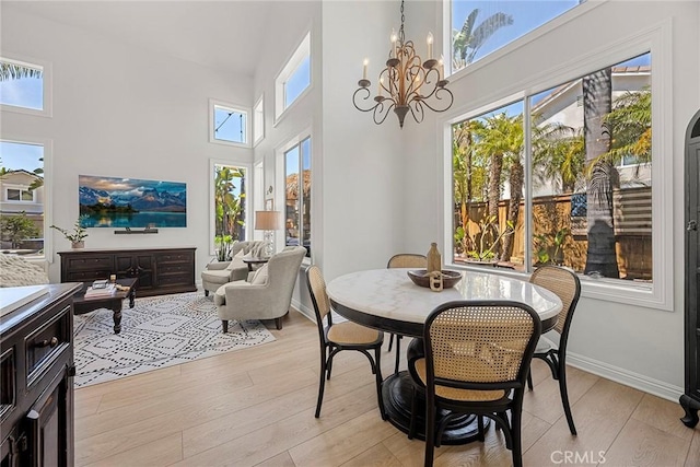 dining room featuring a chandelier, a high ceiling, and light wood finished floors
