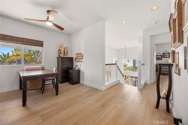 office featuring light wood-style floors, a healthy amount of sunlight, ceiling fan, and baseboards
