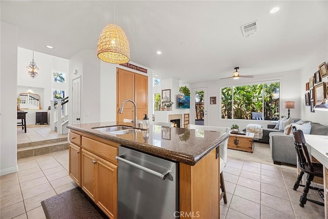 kitchen with a sink, open floor plan, an island with sink, stainless steel dishwasher, and light tile patterned flooring
