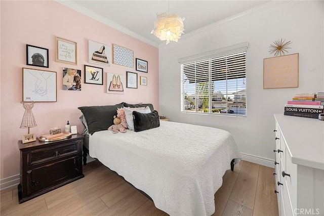 bedroom featuring a chandelier, crown molding, light wood finished floors, and baseboards