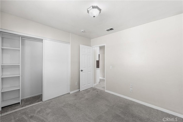 unfurnished bedroom featuring a closet, carpet flooring, baseboards, and visible vents