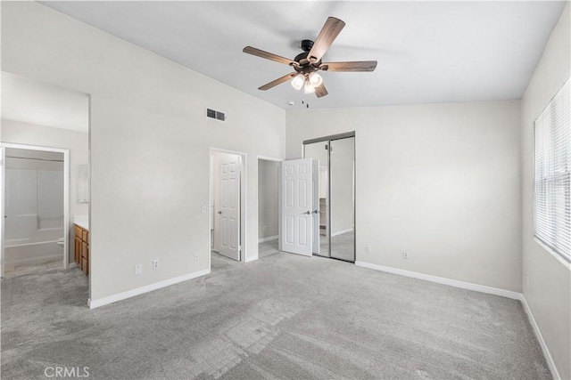 unfurnished bedroom featuring visible vents, baseboards, ensuite bathroom, vaulted ceiling, and light colored carpet