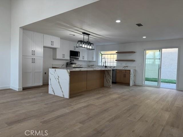 kitchen with open shelves, light wood-type flooring, white cabinetry, stainless steel appliances, and pendant lighting
