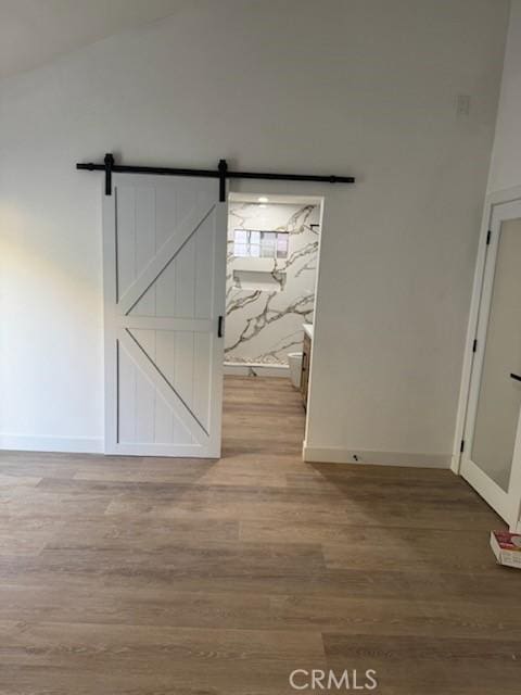interior space with baseboards, a barn door, and wood finished floors