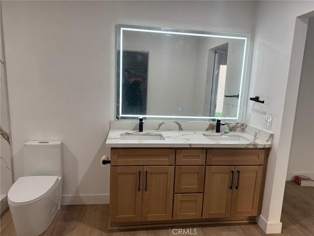 full bath featuring baseboards, wood finished floors, a sink, and double vanity