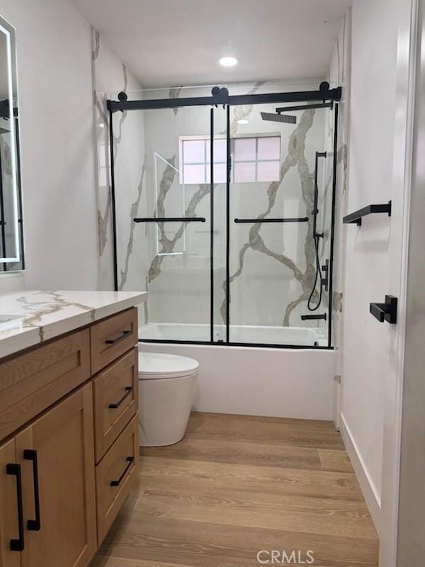 full bath with shower / bath combination with glass door, recessed lighting, wood finished floors, toilet, and vanity
