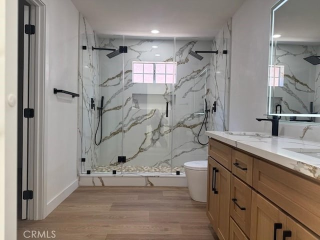 full bathroom featuring toilet, wood finished floors, double vanity, and a marble finish shower
