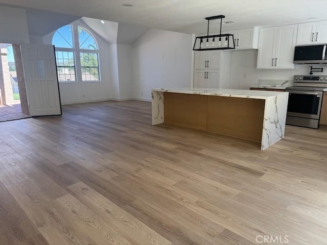 kitchen featuring vaulted ceiling, light wood-style floors, appliances with stainless steel finishes, open floor plan, and white cabinetry