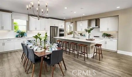 dining area featuring light wood-style floors, a notable chandelier, baseboards, and recessed lighting