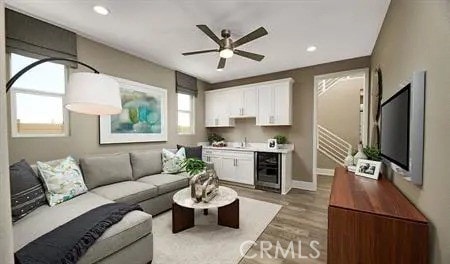 living area with light wood-style flooring, a ceiling fan, recessed lighting, wine cooler, and baseboards