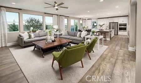 living room featuring light wood-style flooring, baseboards, a ceiling fan, and recessed lighting