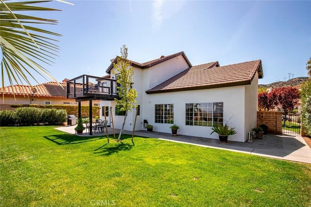 back of property with a patio, stucco siding, fence, and a lawn