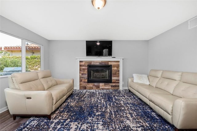 living room with visible vents, baseboards, wood finished floors, and a tile fireplace