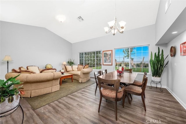 dining room featuring a notable chandelier, baseboards, visible vents, lofted ceiling, and wood finished floors