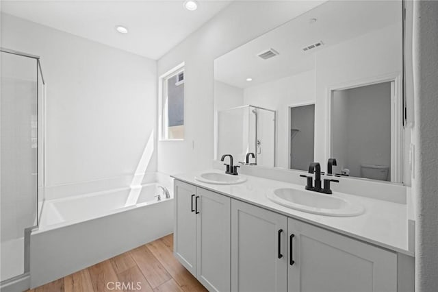 bathroom featuring a bath, wood finished floors, a shower stall, and a sink