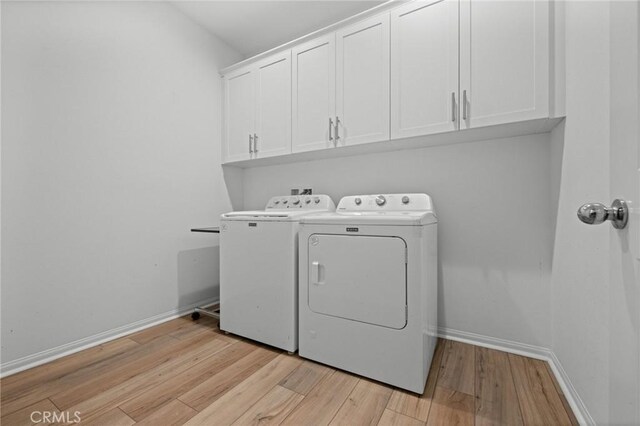 washroom with light wood finished floors, cabinet space, baseboards, and washer and dryer