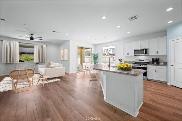 kitchen with a sink, dark stone counters, visible vents, recessed lighting, and appliances with stainless steel finishes