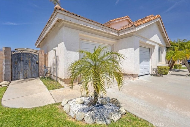 3594 N Verbena, Rialto, CA 92377 - view of side of property featuring a gate, stucco siding, a garage, a tile roof, and driveway