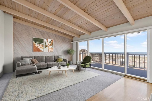 living area featuring wooden walls, a water view, lofted ceiling with beams, and wood ceiling