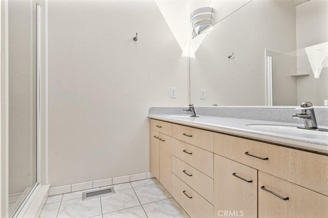 bathroom with a sink, a shower stall, double vanity, and visible vents
