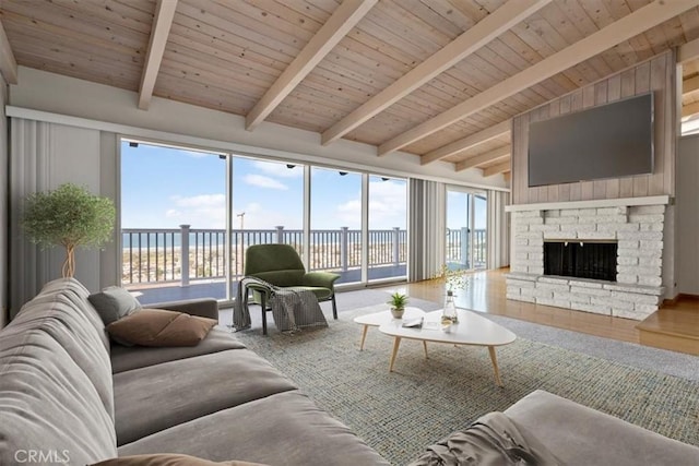 living area featuring a fireplace with raised hearth, lofted ceiling with beams, and wooden ceiling