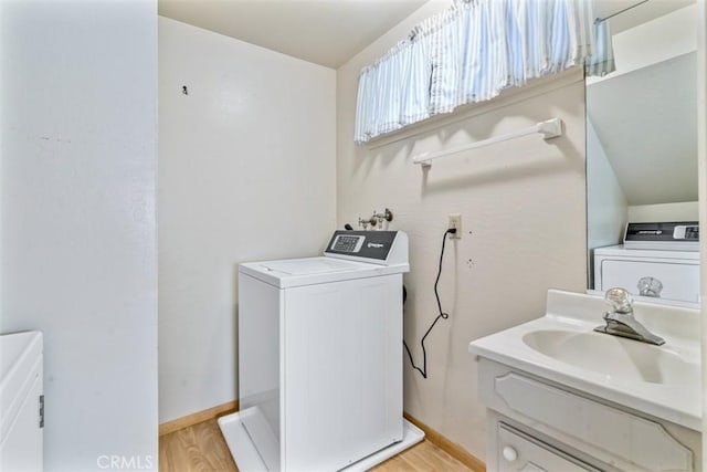laundry area with a sink, baseboards, independent washer and dryer, and light wood-style flooring