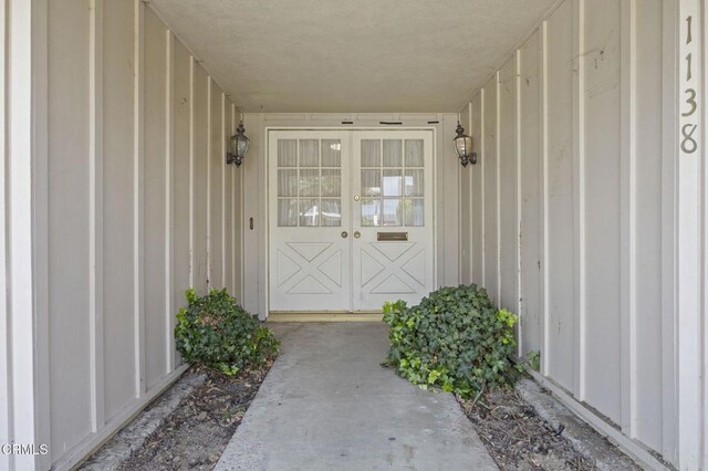 property entrance featuring board and batten siding and french doors