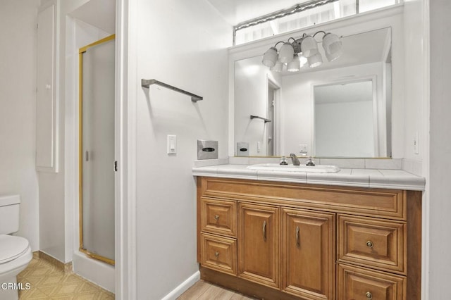 full bathroom with toilet, a stall shower, vanity, and baseboards