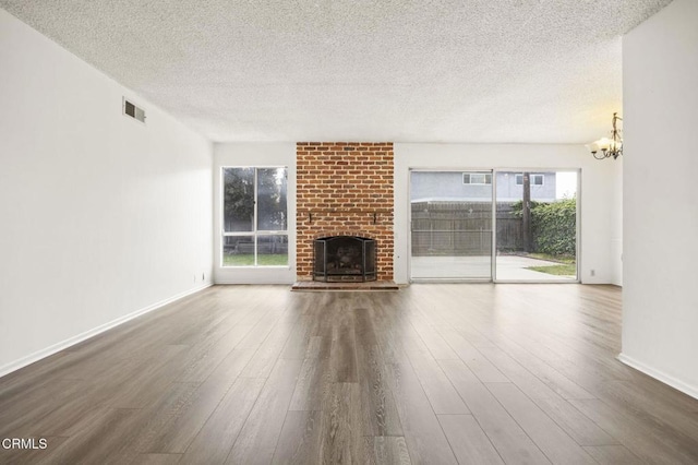 unfurnished living room featuring a textured ceiling, a chandelier, wood finished floors, and a fireplace