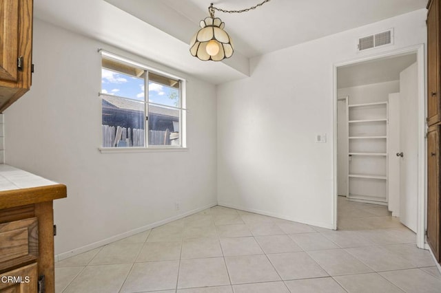 unfurnished dining area featuring baseboards, visible vents, and light tile patterned floors