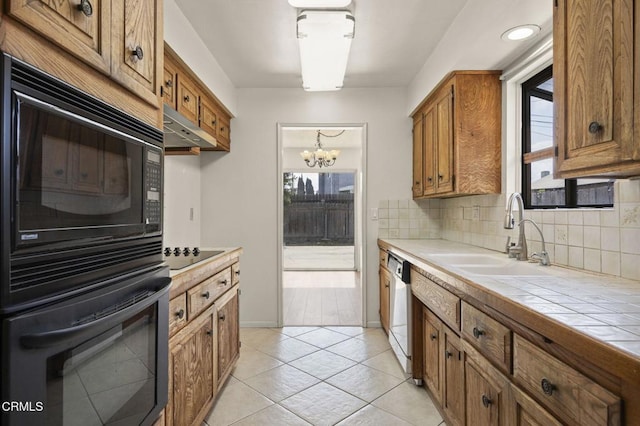 kitchen featuring black appliances, a sink, tile counters, and brown cabinetry