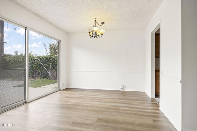 unfurnished dining area with a chandelier, light wood-style floors, and a textured ceiling