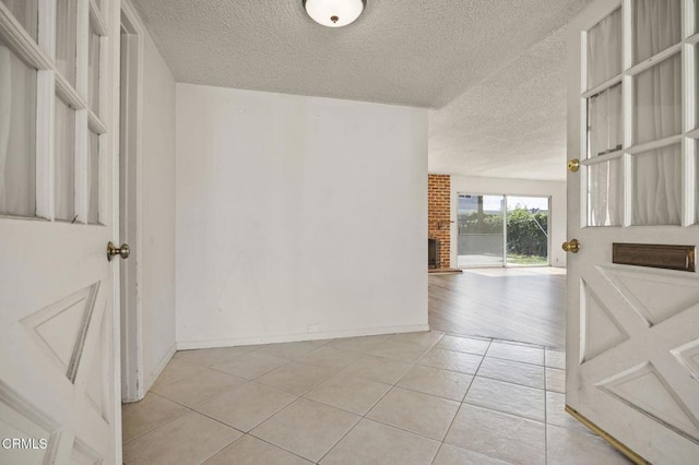 interior space featuring light tile patterned flooring, a textured ceiling, and baseboards