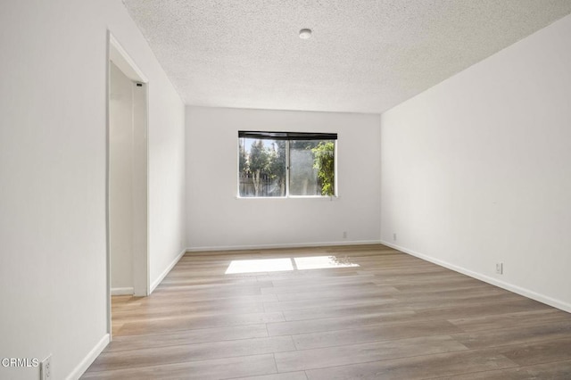 unfurnished room with baseboards, wood finished floors, and a textured ceiling