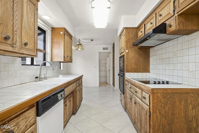 kitchen featuring black appliances, a sink, tile countertops, and under cabinet range hood