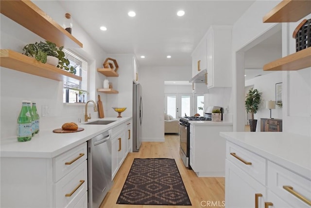 kitchen with under cabinet range hood, white cabinetry, open shelves, and appliances with stainless steel finishes