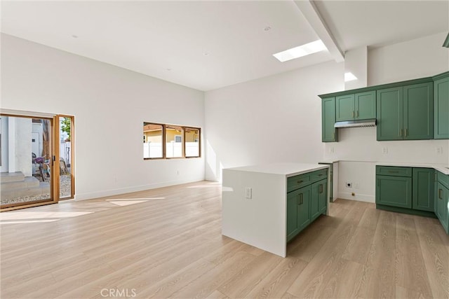 kitchen with green cabinets, light wood finished floors, a skylight, and a wealth of natural light