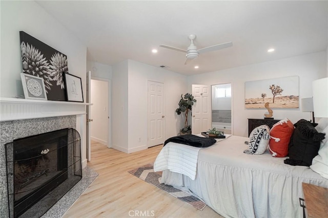 bedroom with recessed lighting, a fireplace, baseboards, and wood finished floors