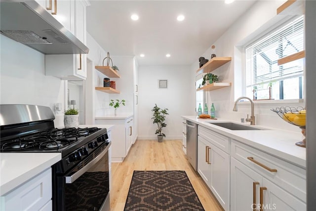 kitchen featuring gas stove, open shelves, under cabinet range hood, light wood-style floors, and a sink