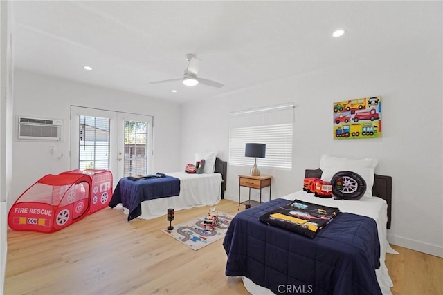 bedroom featuring french doors, a ceiling fan, access to exterior, a wall unit AC, and wood finished floors