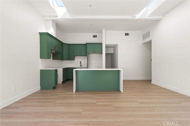 kitchen with visible vents, a skylight, light wood finished floors, and green cabinetry