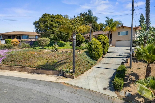 view of front facade featuring a tiled roof, a garage, stucco siding, and concrete driveway