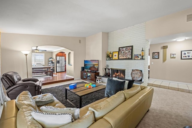 living room with carpet floors, arched walkways, and a fireplace