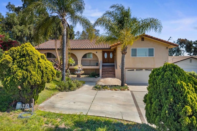 mediterranean / spanish home featuring stucco siding, driveway, an attached garage, stairs, and a tiled roof