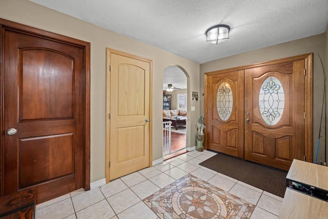 foyer entrance featuring light tile patterned floors, baseboards, and a textured ceiling