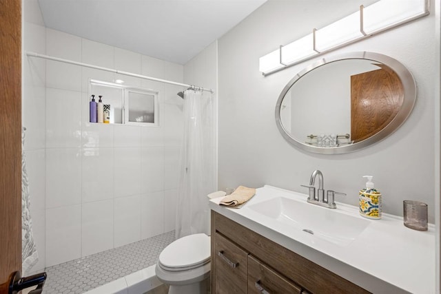 full bath with vanity, a tile shower, and toilet